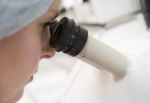 A scientist looks into a microscope in search for a cure for HIV. The ethics of research is important in finding solutions.