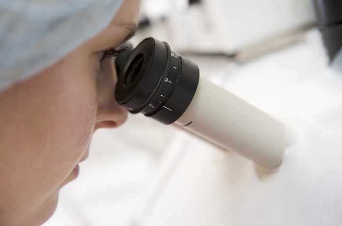 A scientist looks into a microscope in search for a cure for HIV. The ethics of research is important in finding solutions.