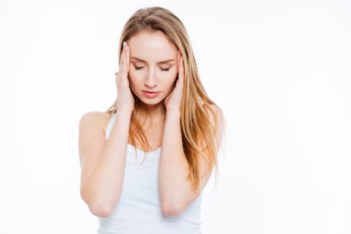 A person holding her head in pain due to a migraine headache. Thankfully, alternative treatments to drugs may be a source of comfort for migraine headache sufferers.