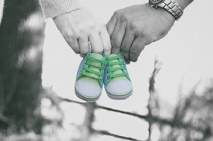 baby shoes held by mother's and father's hands