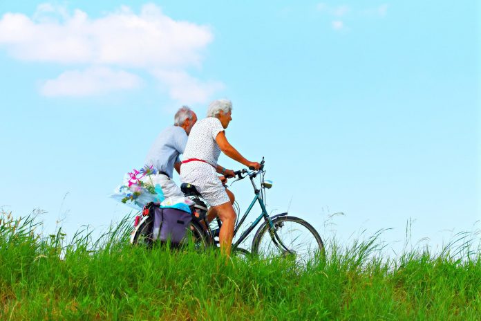 A youthful geriatric couple cycling in nature showing that lifestyle factors are more important than aging for dementia risk.