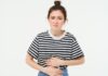 Vulnerable to Crohns: Woman feeling hungry, touching her belly. Girl with period cramps, menstrial pain, holds hands on stomach that aches, isolated over white background