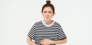 Vulnerable to Crohns: Woman feeling hungry, touching her belly. Girl with period cramps, menstrial pain, holds hands on stomach that aches, isolated over white background