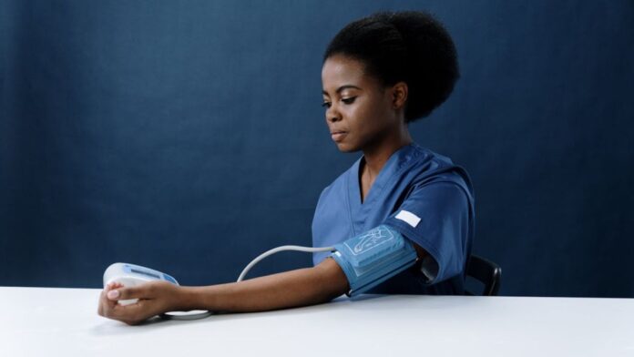 Photo of a woman taking her blood pressure with a blood pressure device.