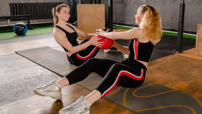 Photo of 2 women helping each other while doing aerobic exercises.